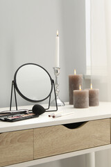 Dressing table with mirror, cosmetic products and burning candles in makeup room