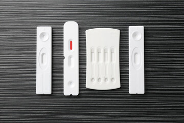 Different disposable express tests on black wooden table, flat lay