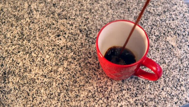 Sirviendo cafe expreso en taza roja recién hecho caliente y saliendo vapor llenando el recipiente