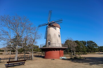 Fototapeta na wymiar 青空バックに見る古い風車小屋のある公園の情景
