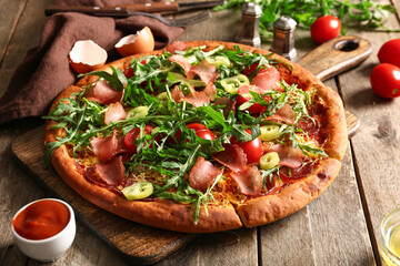 Board of delicious pizza with tomatoes and arugula on wooden background