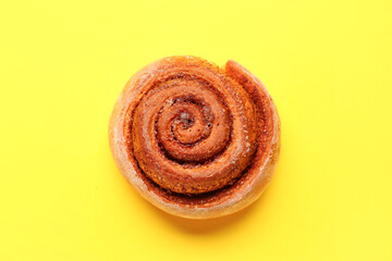 Tasty cinnamon roll on yellow background