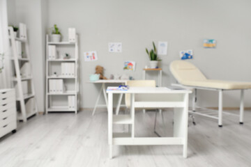Blurred view of pediatrician's office with table, couch and children's drawings