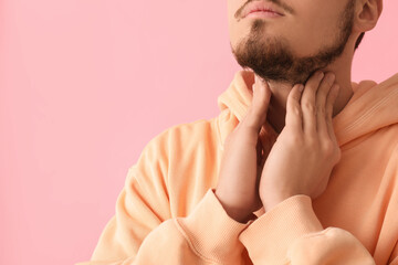 Fototapeta premium Young man with thyroid gland problem on pink background, closeup