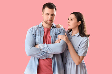 Sad young couple hugging on pink background