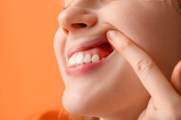 Obraz premium Teenage girl showing her teeth on orange background, closeup