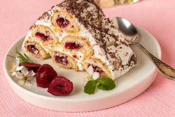Piece of cake with cherry filling on white plate. Pink background