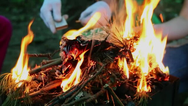 People add paper burning branches in brazier at evening