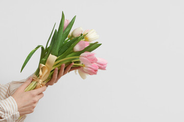 Female hands with bouquet of beautiful tulips on white background. International Women's Day