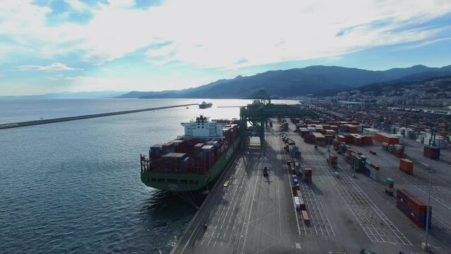 Container terminal Voltri Europa with barge on moorage and cityscape
