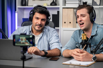 Host channel of creative broadcaster living by smartphone in positive podcast with special guest in list script to advice listeners, wearing headsets, using mic radio record at studio. Sellable.