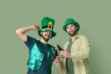 Young men in leprechaun hats with green beards holding bottles of beer on green background. St....
