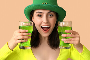 Happy young woman in leprechaun hat with glasses of beer on brown background. St. Patrick's Day...