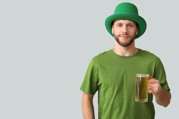 Young man in leprechaun hat with glass of beer on grey background. St. Patrick's Day celebration
