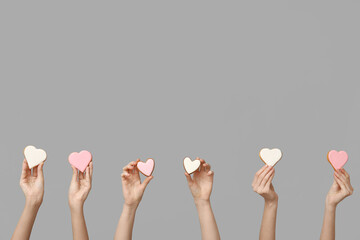 Women with heart-shaped cookies on grey background. Valentine's Day celebration