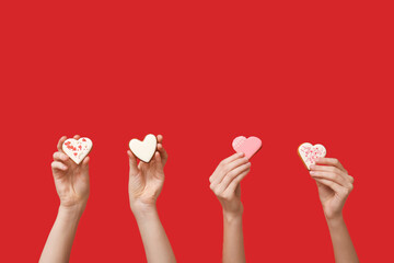 Women with heart-shaped cookies on red background. Valentine's Day celebration