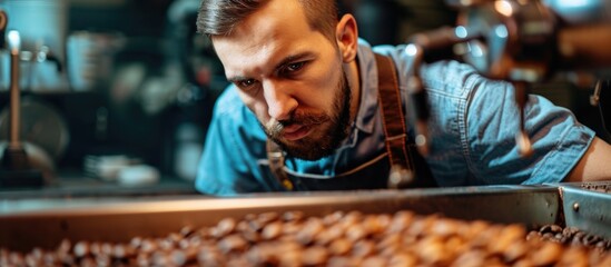 Good-looking worker evaluates coffee quality after roasting in factory machine using sniffing.