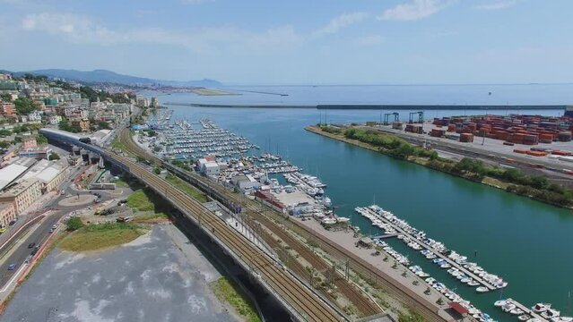 Train rides by railroad near port at summer day. Aerial view