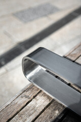 Stainless steel armrests design on wooden chair in outdoors.