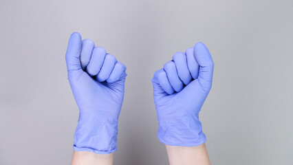 Hands in blue gloves of doctor or nurse over grey background with copy space. Medical gloves.