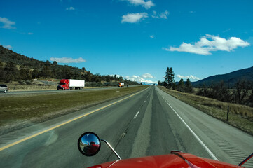 Looking Out the Windshield Down the Highway Towards a Snowcapped Mountain