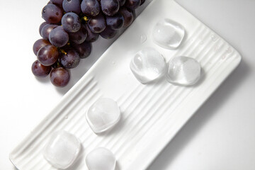 Bunch of grapes on top of white plate with ice. Summer concept.