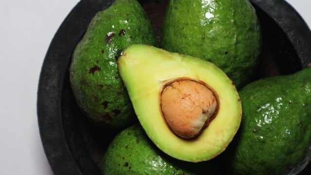 Fresh avocado slice on the wooden plate with rotating background. Top view concept.