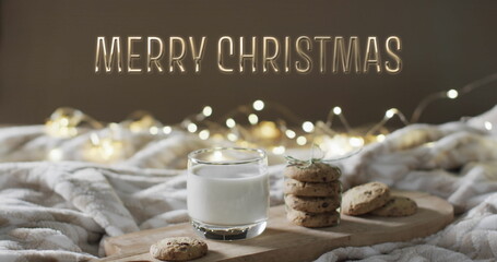 Merry christmas text over christmas cookies and milk with string lights in background
