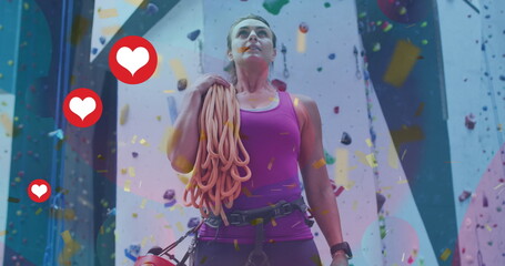 Image of heart icons over caucasian woman on climbing wall