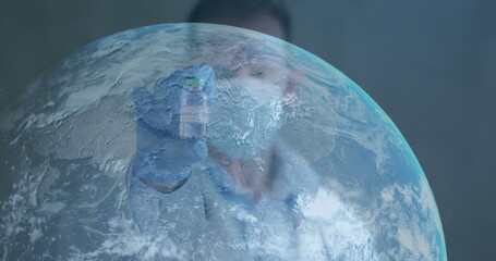 Image of globe with scientist holding covid-19 vaccine wearing face masks