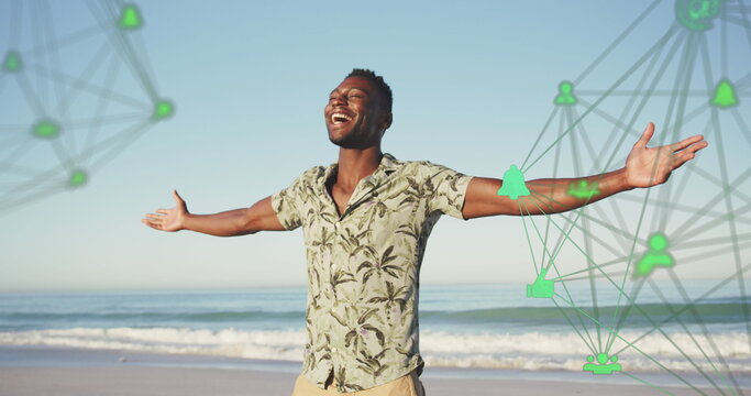 Image of spinning networks with social media digital icons over smiling man on beach