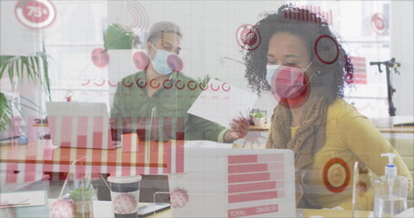 Image of digital interface showing statistics with colleagues in office wearing face masks
