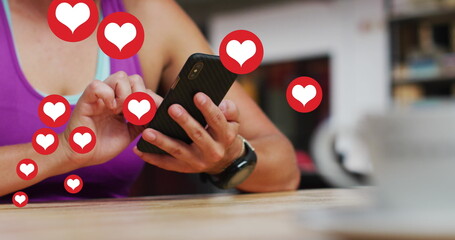 Multiple heart icons floating against mid section of caucasian woman using smartphone