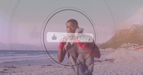 Speech bubble with increasing likes against african american male boxer practicing boxing at beach
