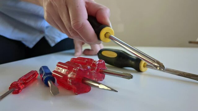 Woman choosing and grabbing screwdriver of multiple screwdrivers, close up