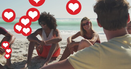Image of social media heart icons over smiling group of friends on beach
