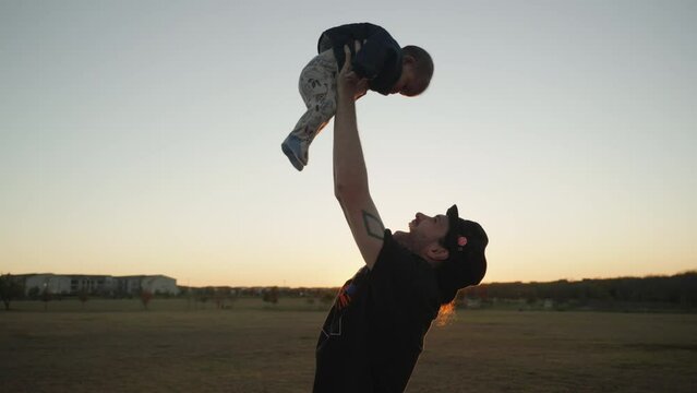 Tattoo'd caucasian dad enjoying father son time with his baby in a neighborhood park. Slow motion