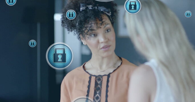 Image of padlock icons data processing over diverse businesswomen in office - Powered by Adobe