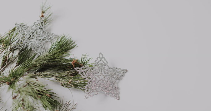 A silver snowflake ornament rests beside pine branches, with copy space