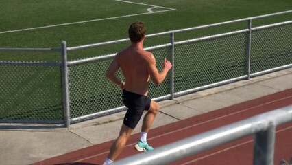 Slow Motion Of A Shirtless Guy With Muscular Body Running On A Sports Track.