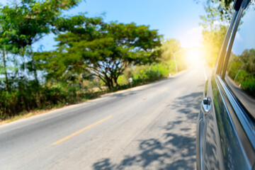View on the side of car showing the windows and shiny light of car. Driving on asphalt road the...