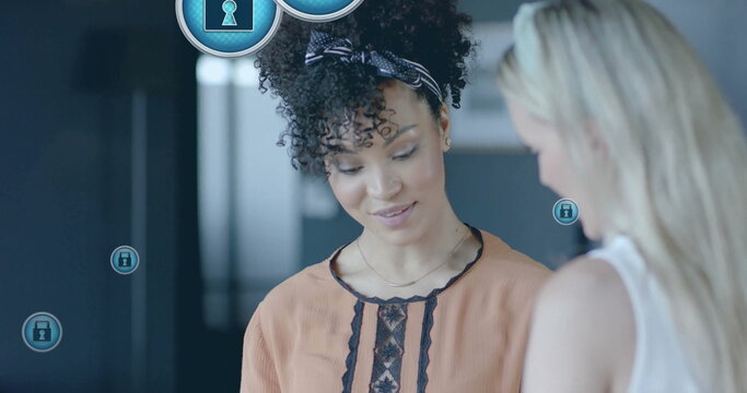 Image of padlock icons data processing over diverse businesswomen in office - Powered by Adobe