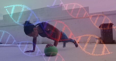 Image of dna strands spinning over woman doing press ups, exercising with ball in gym
