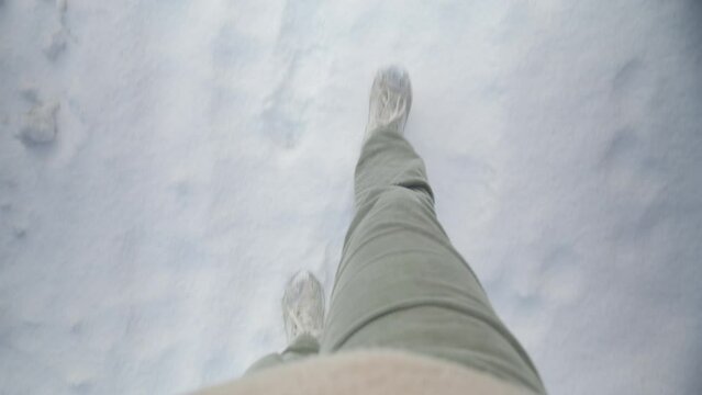 POV walking through a snow-covered path with footprints.