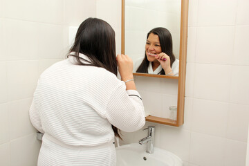 Latina 40 year old woman brushes and takes care of her teeth to prevent cavities dressed in...