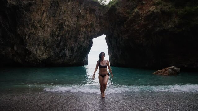 Woman walking out of water after a swim in Spiaggia dell'Arcomagno beach Calabria Italy