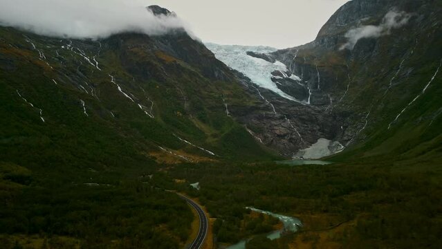 Drone flies away from a Norwegian Gletcher. You can see mountains in the Norwegian highlands