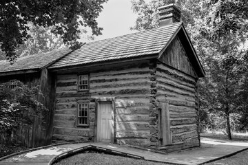 black and white photograph of small wooden cabin in the woods
