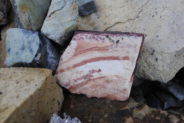 Square rock with red, white, and orange striations on stone background
