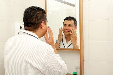 40-year-old dark-skinned Latin man does skin care in the morning and at night with serum, cream and...